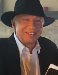A man in a black hat holding a book.