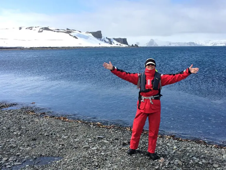 solo traveller in red polar gear on land of Antarctica