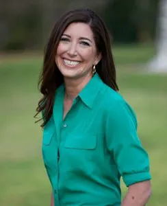 A woman in a green shirt smiles for the camera.