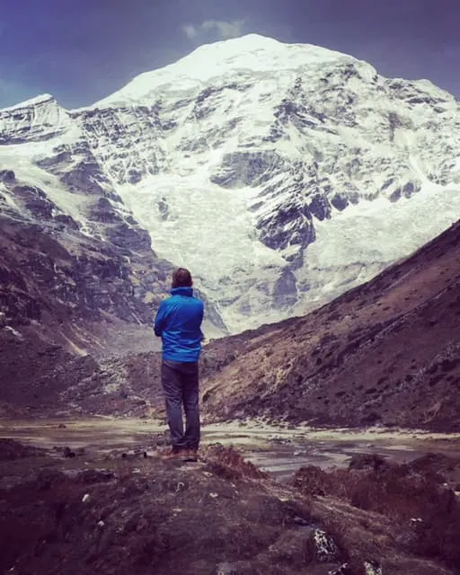A man standing in front of a snow covered mountain.
