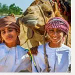 Two boys are posing for a photo with a camel.