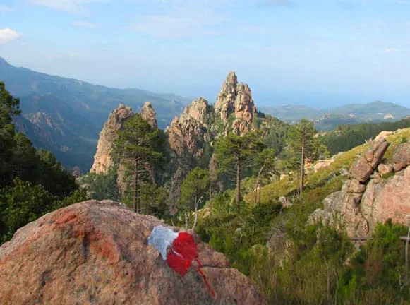 A red and white flag sits on top of a rock in the mountains.