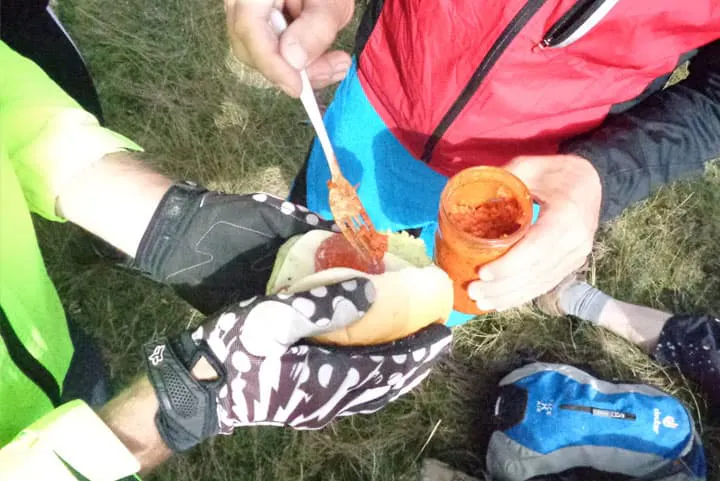 A man is eating a hot dog with a spoon.