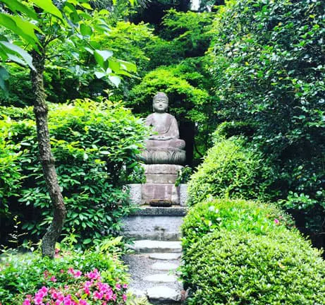 A japanese garden with a buddha statue in the middle.