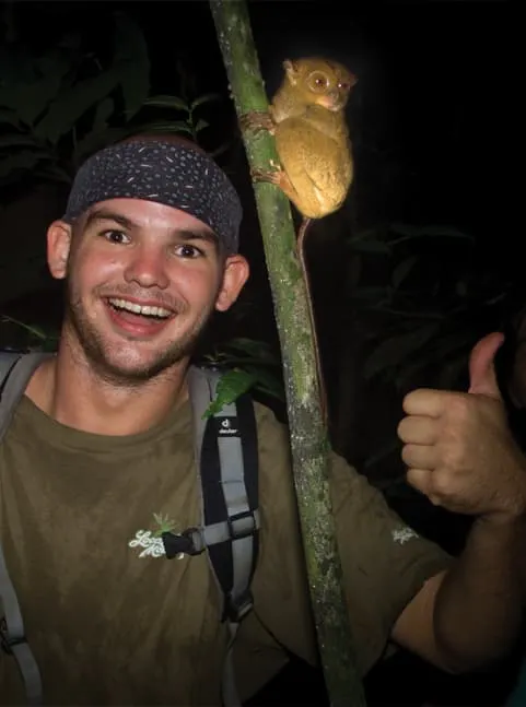 A man with a backpack holding a small monkey.