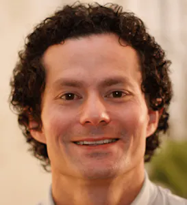 A man in a white shirt with curly hair.