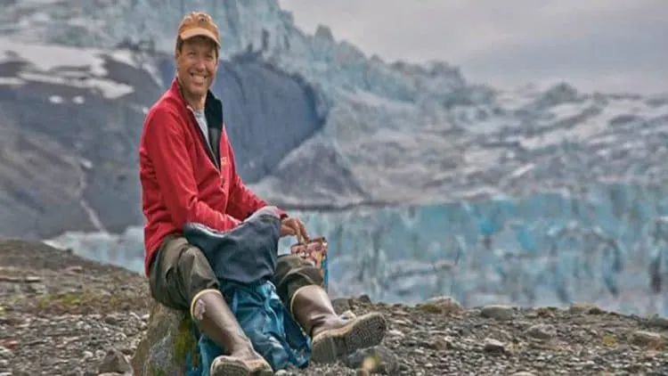 A man sitting on a rock in front of a glacier.