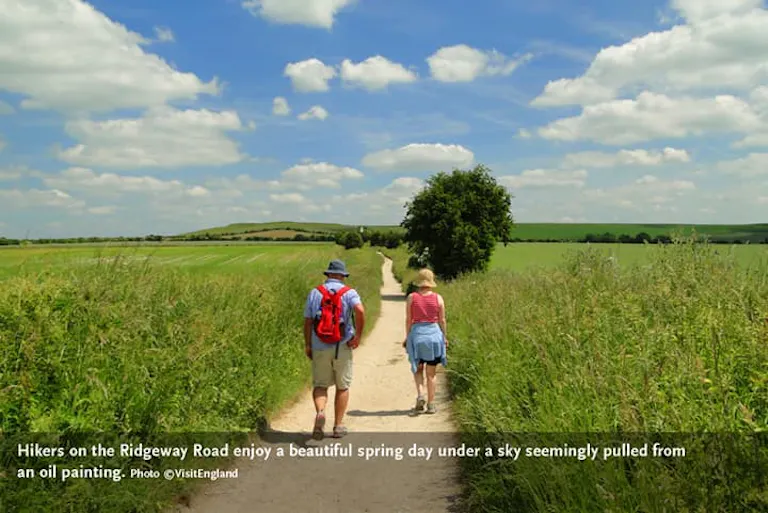 A couple female and male walking with recreational equipment on the English Cotswolds' Ridgeway Road