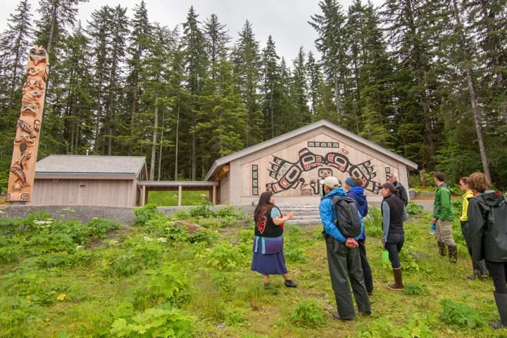 A group of people standing in front of a totem pole.