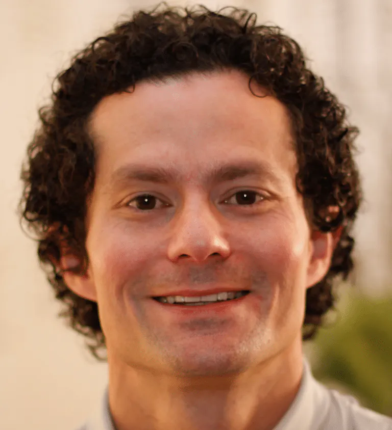 A man in a white shirt with curly hair.