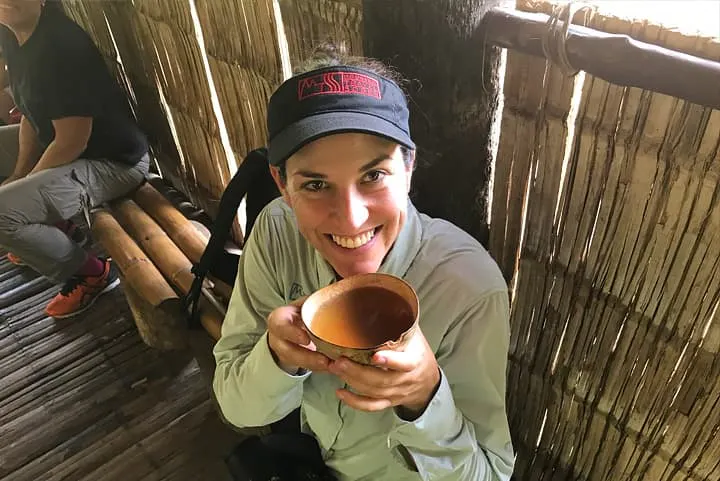 A woman holding a cup of tea in a bamboo hut.