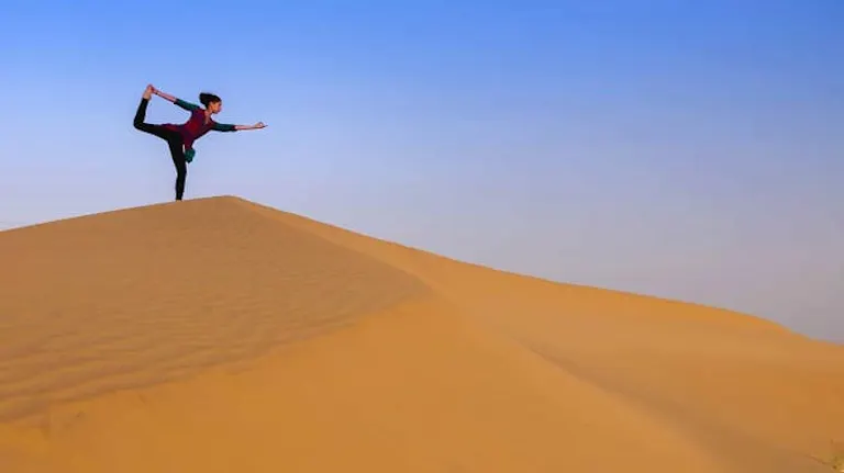 A woman is standing on top of a sand dune.