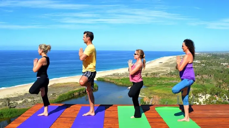 A group of people doing yoga on a deck overlooking the ocean.