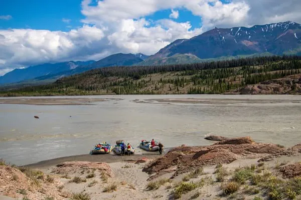 A group of people on rafts on a river with mountains in the background.