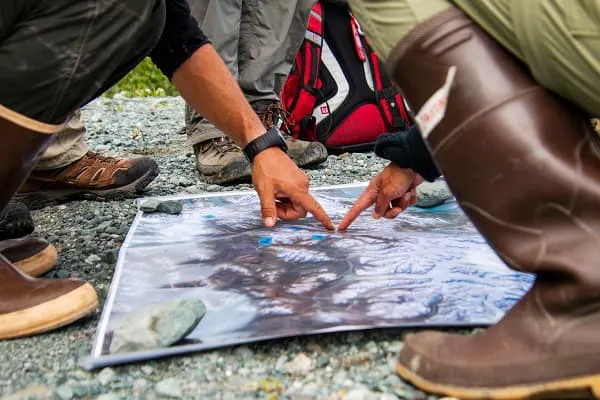 A group of people pointing to a map on the ground.