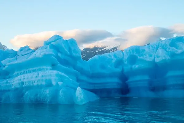 A blue iceberg floating in the water.