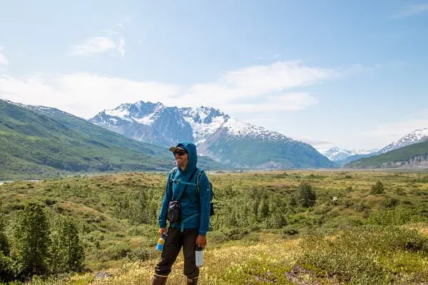 A woman standing in a field with mountains in the background.