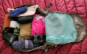 The contents of a backpack on a bed.