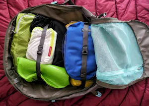 A bag filled with various items on a bed.