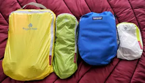A group of bags with different colors sitting on top of a bed.