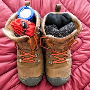 A pair of brown hiking boots on a bed.