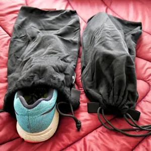A pair of black shoe bags on a bed.