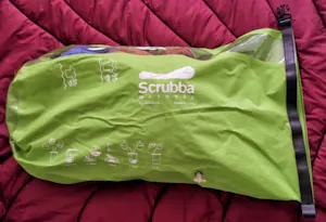 A green bag is sitting on top of a bed.