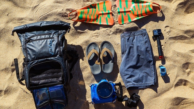 A backpack and other items laid out on the sand.
