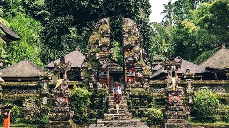 A woman standing in front of a temple in bali.