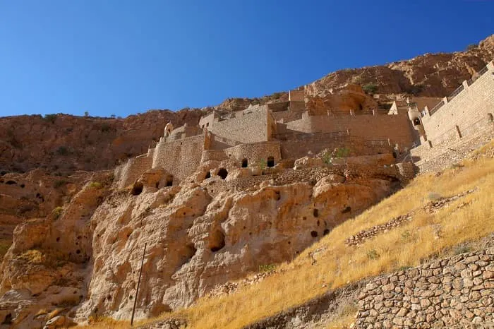 The ruins of a castle on the side of a cliff.