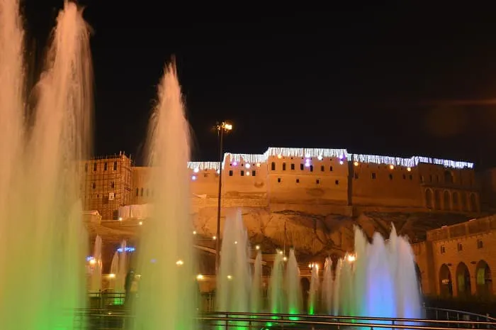 Fountains in front of a castle at night.