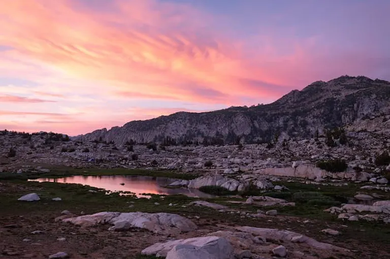 A pink sunset over a lake in the mountains.