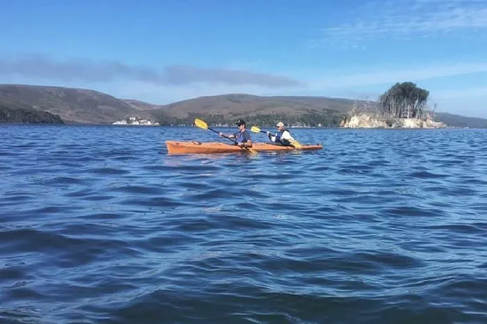 Two people paddling in a kayak on a body of water.