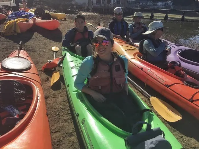 A group of people sitting in kayaks on the beach.