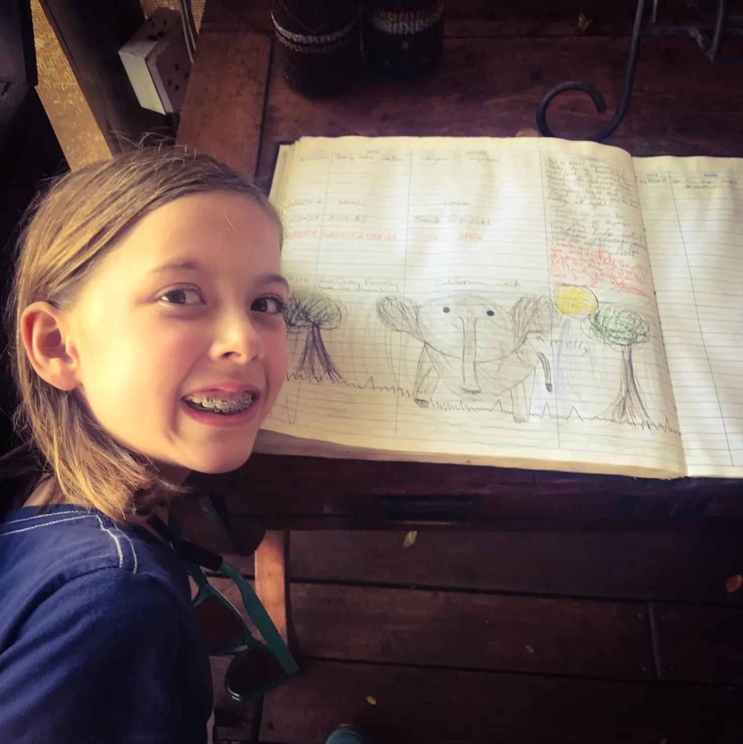 A girl sitting at a table with a notebook in front of her.