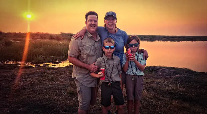 A family is posing for a photo in front of a lake.