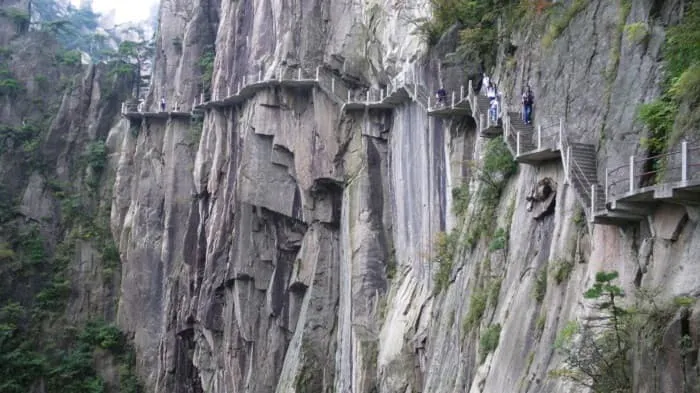 A group of people are walking up a steep cliff.