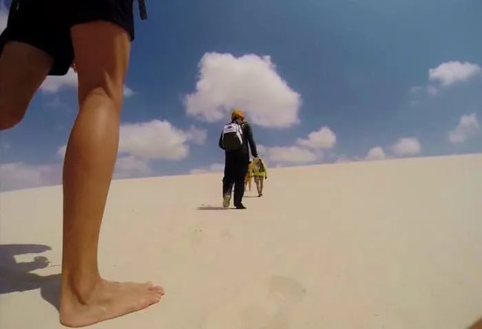 A group of people walking on a sand dune.