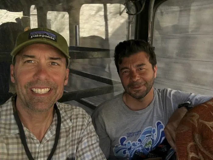 Three men smiling while sitting on a bus.