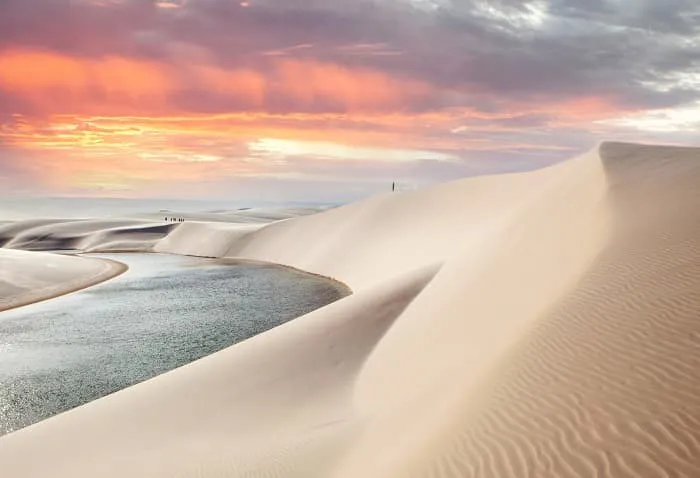A sand dune with a river in the background.