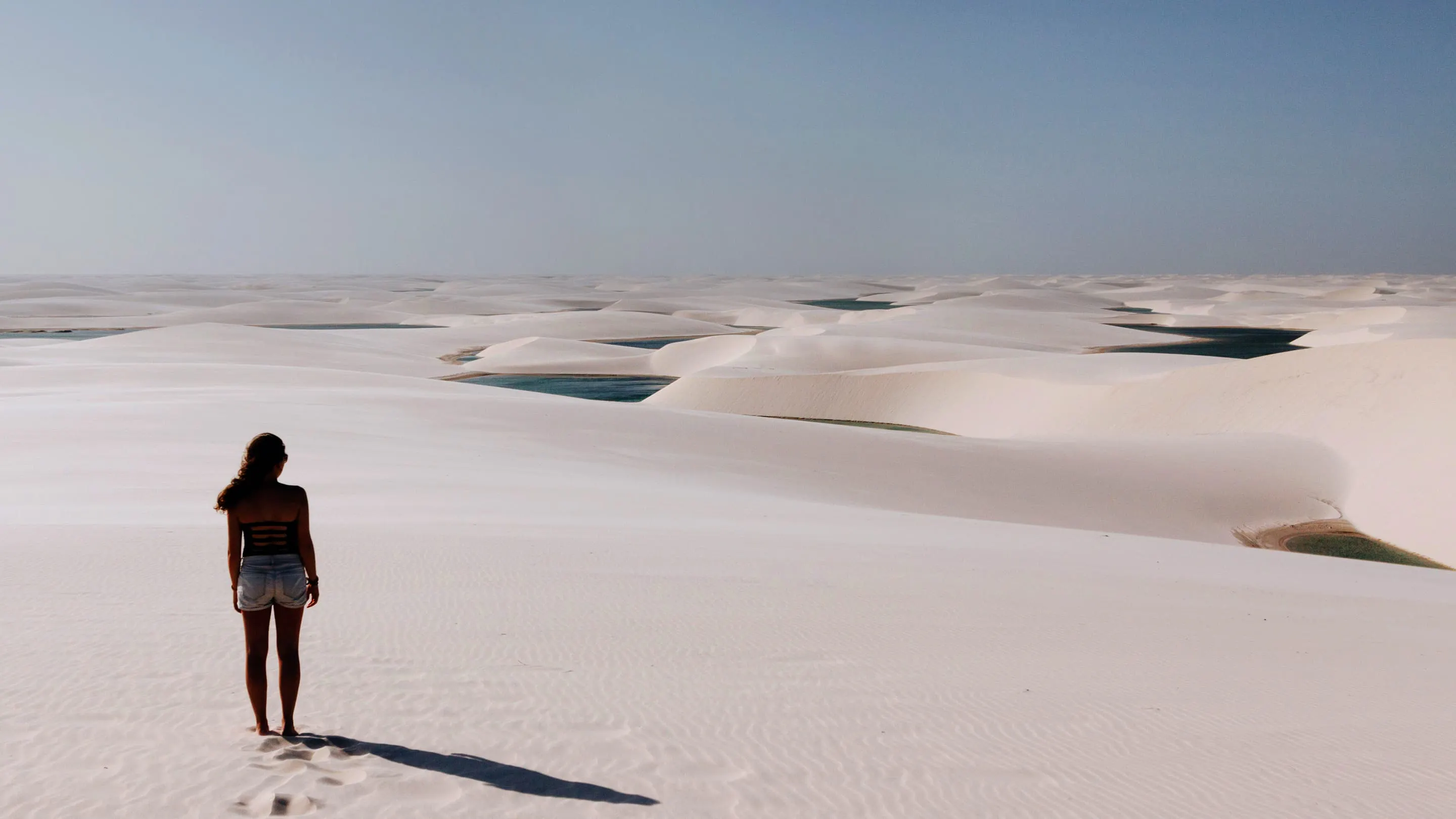 A woman standing on top of a white sand dune.