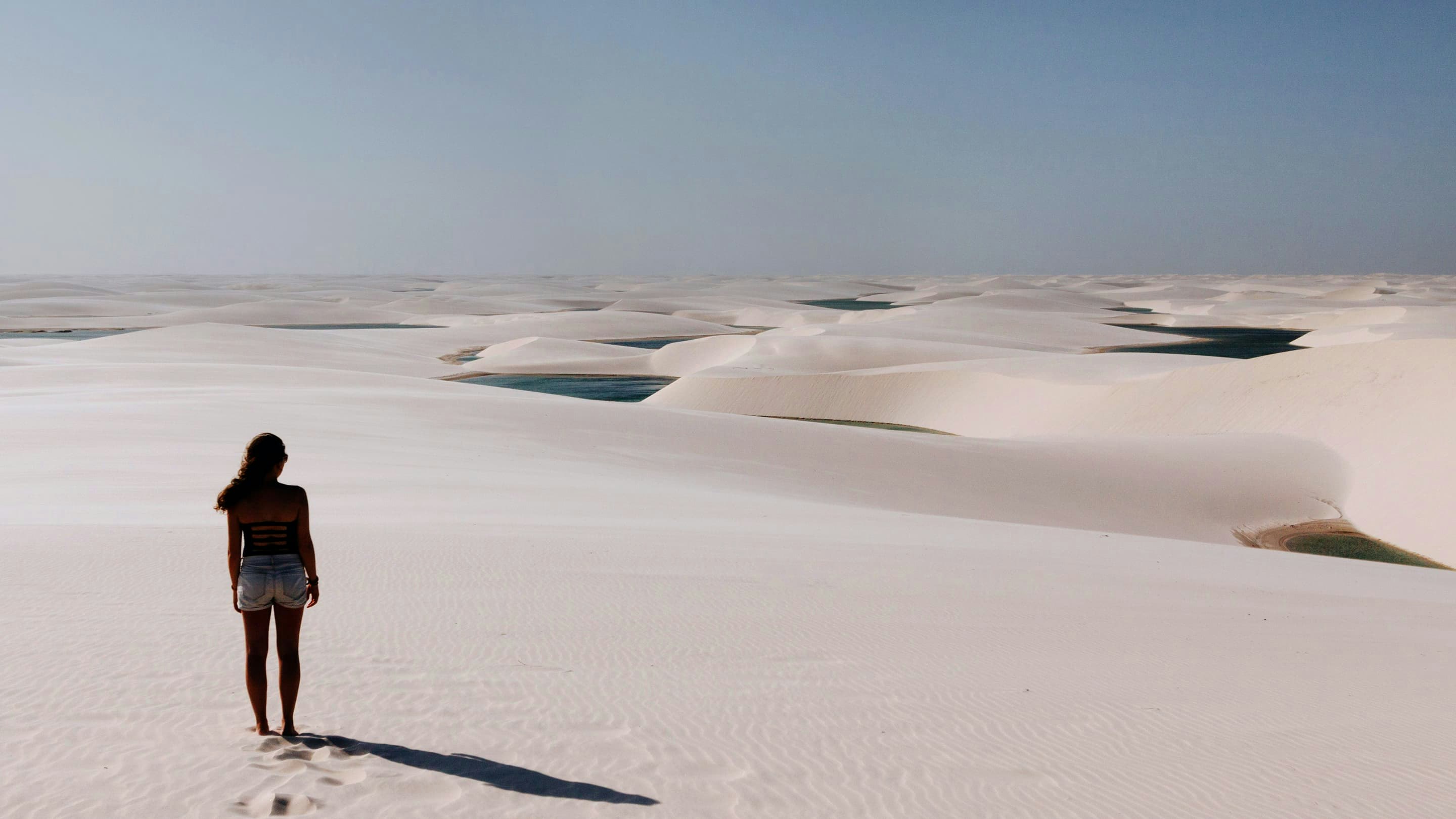 A woman standing on top of a white sand dune.
