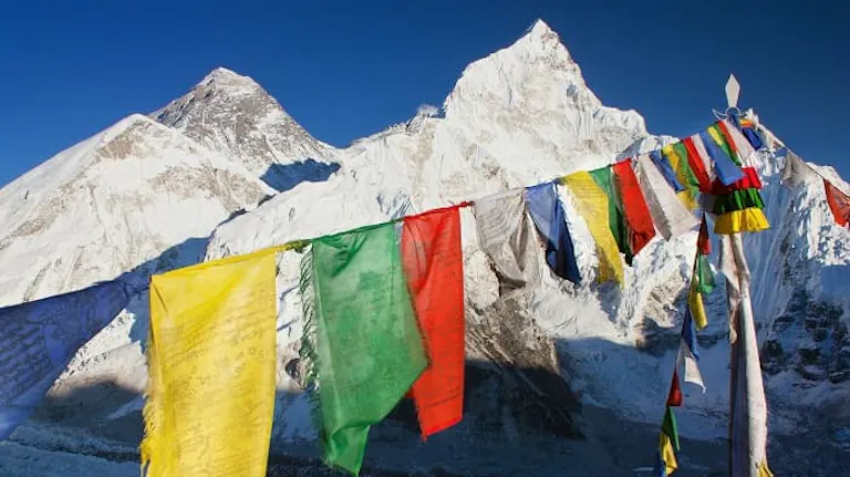 A group of prayer flags in front of a snowy mountain.