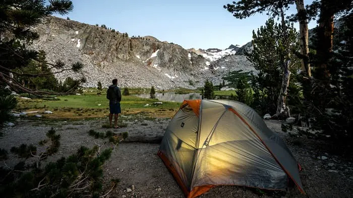 A man is setting up a tent in the mountains.