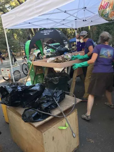 A group of people standing under a tent with trash bags.