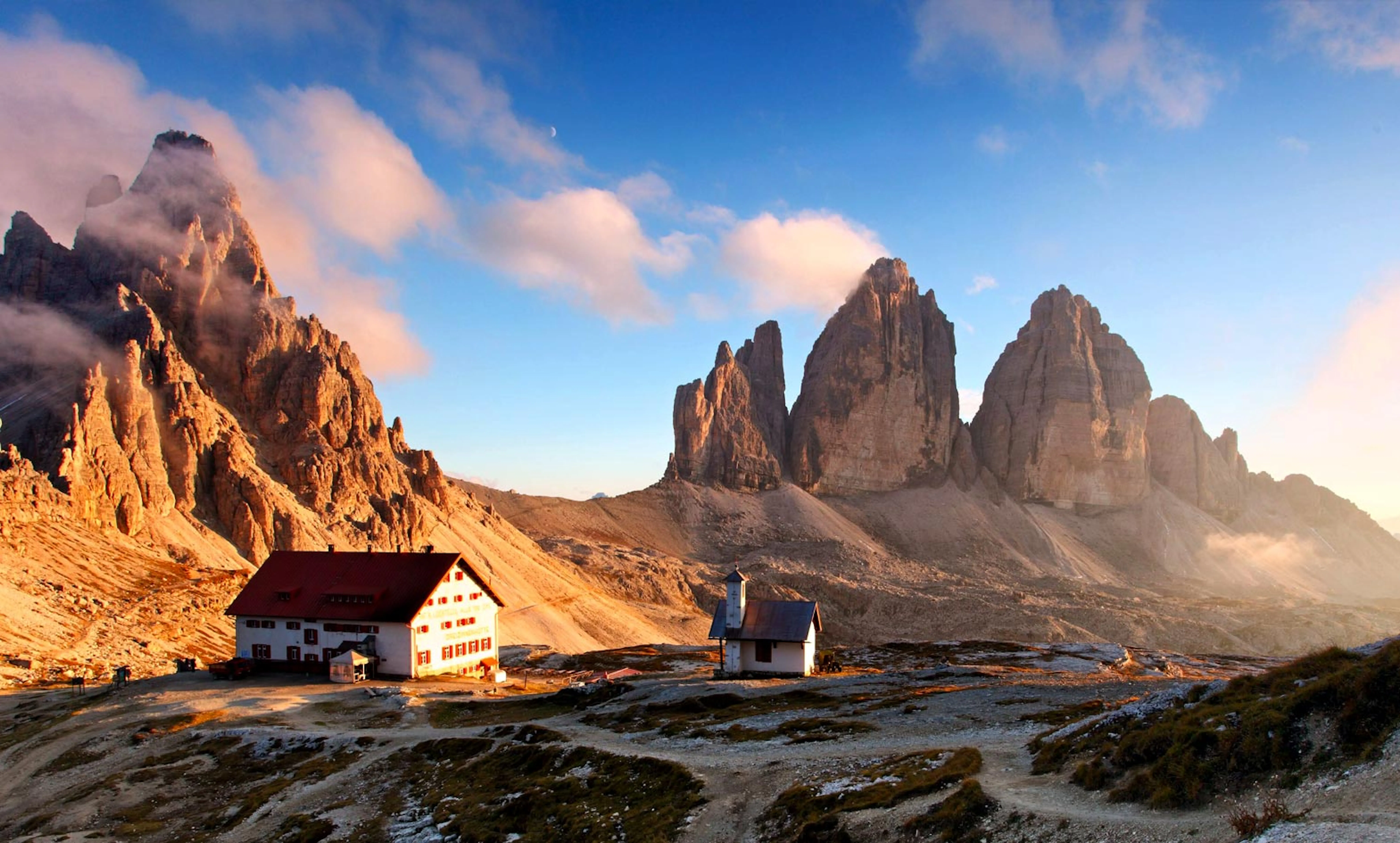A house sits on top of a mountain in the dolomites.