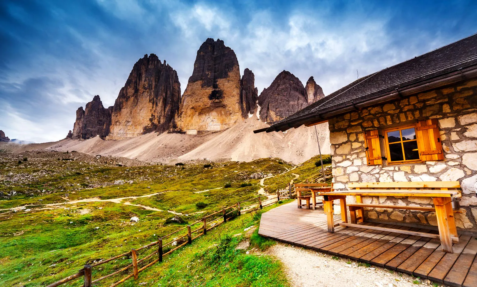 A stone cabin in the mountains with mountains in the background.