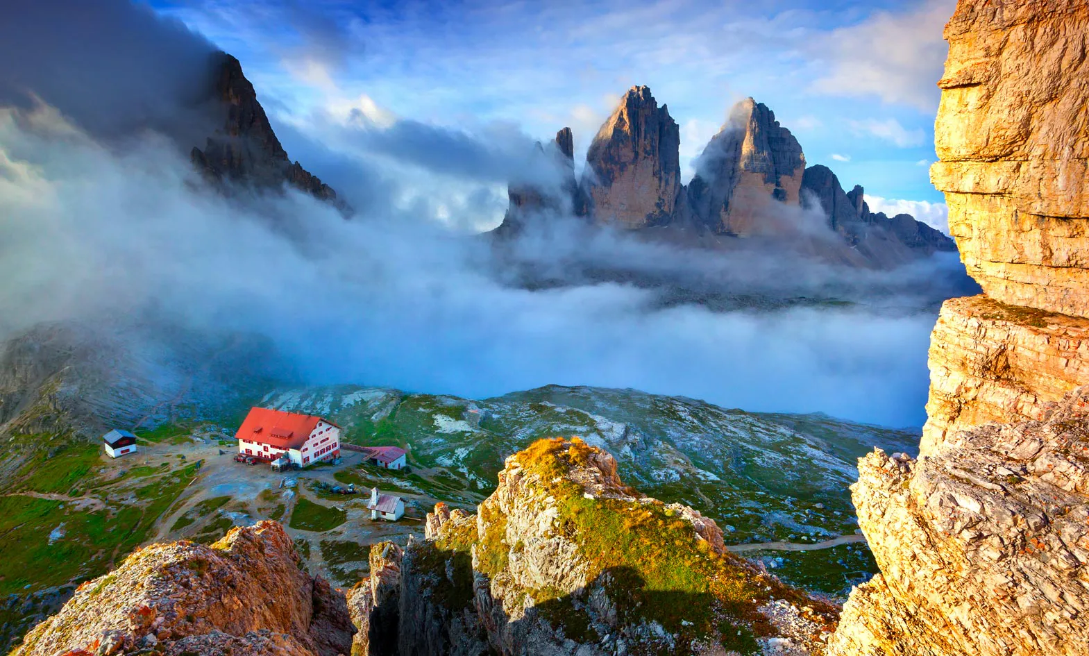 A house on top of a mountain with clouds in the background.