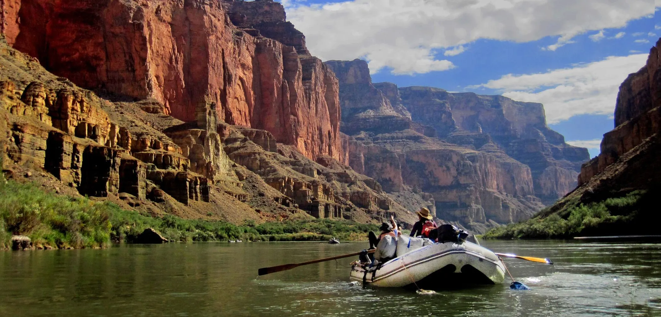 A group of people on a boat experiencing cataract canyon white water rafting.