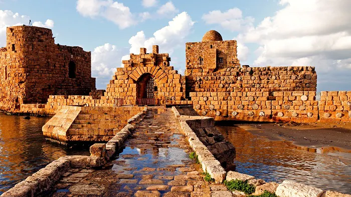 A castle with a stone walkway next to a body of water.